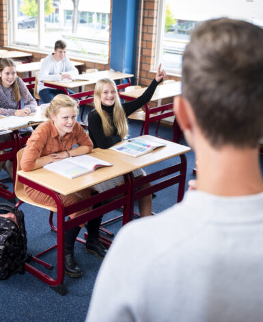 Leerlingen in de klas van locatie Goes Klein Frankrijk. Leerling steekt vinger op voor een vraag.