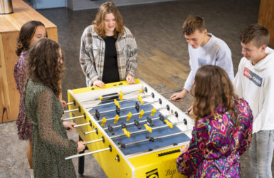 Leerlingen van locatie Krabbendijke Kerkpolder spelen samen een potje voetbal rond de voetbaltafel in de aula