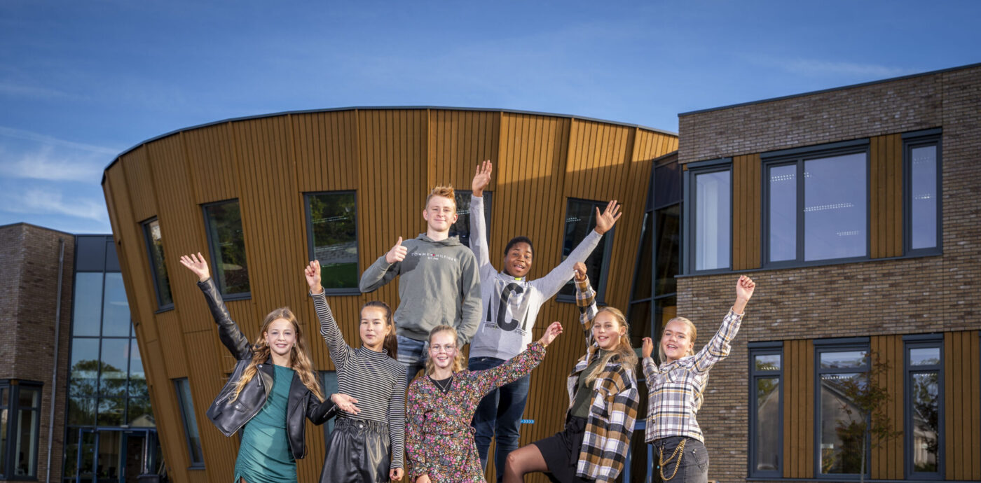 Leerlingen steken enthousiast de handen op op het plein van locatie Middelburg