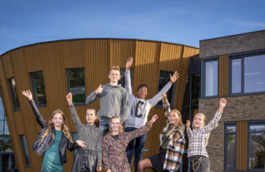 Leerlingen steken enthousiast de handen op op het plein van locatie Middelburg