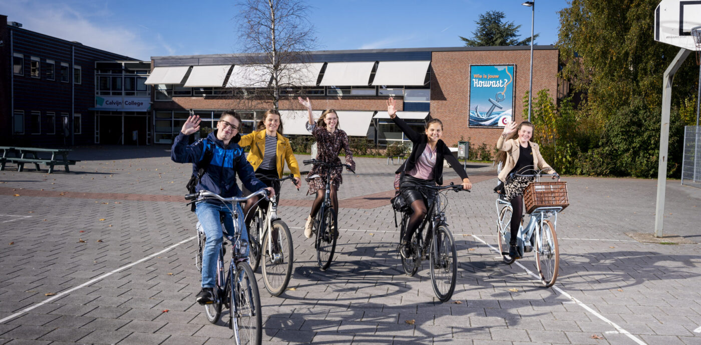 Leerlingen fietsen van het plein af en zwaaien in de camera