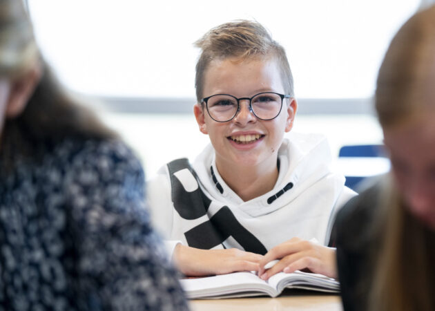 Leerling op de middelbare school, met boek op tafel.