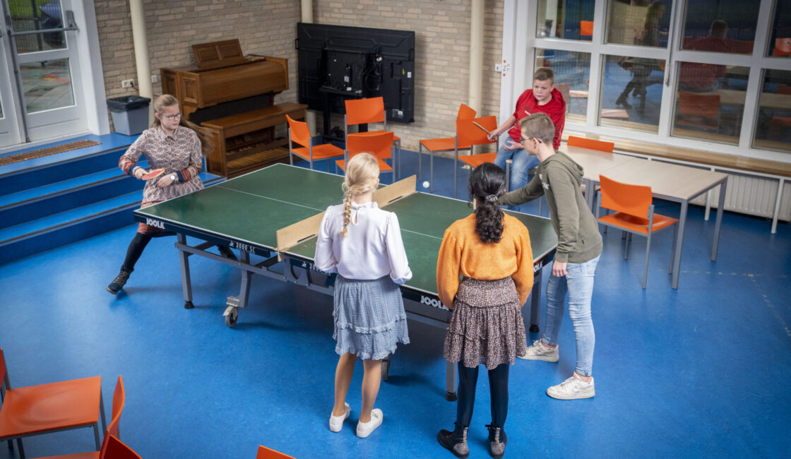 Leerlingen spelen een potje tafeltennis in de aula.