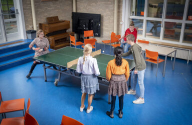 Leerlingen spelen een potje tafeltennis in de aula.