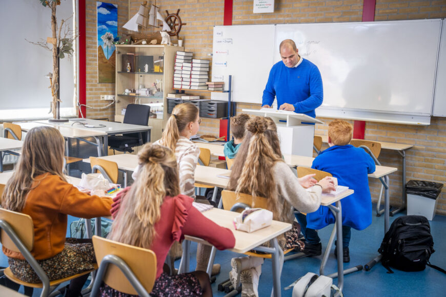 Leerlingen luisteren samen naar de docent in de klas