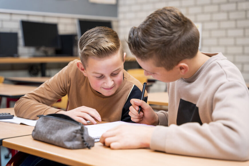 Leerlingen kijken samen in een boek en leren samen