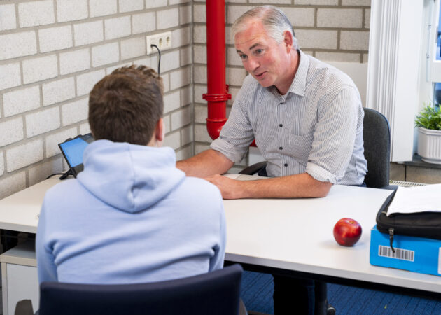 Docent en leerling hebben een gesprekje. Persoonlijke begeleiding en maatwerk zijn speerpunten op het Calvijn College