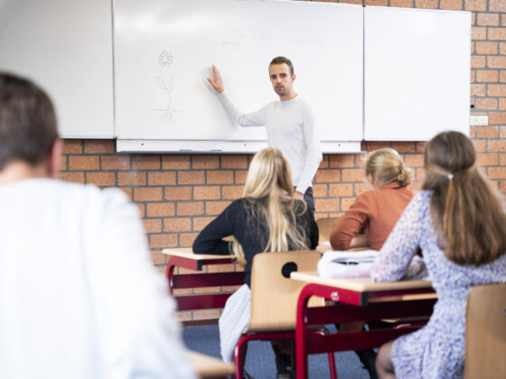 Docent geeft uitleg in klaslokaal.