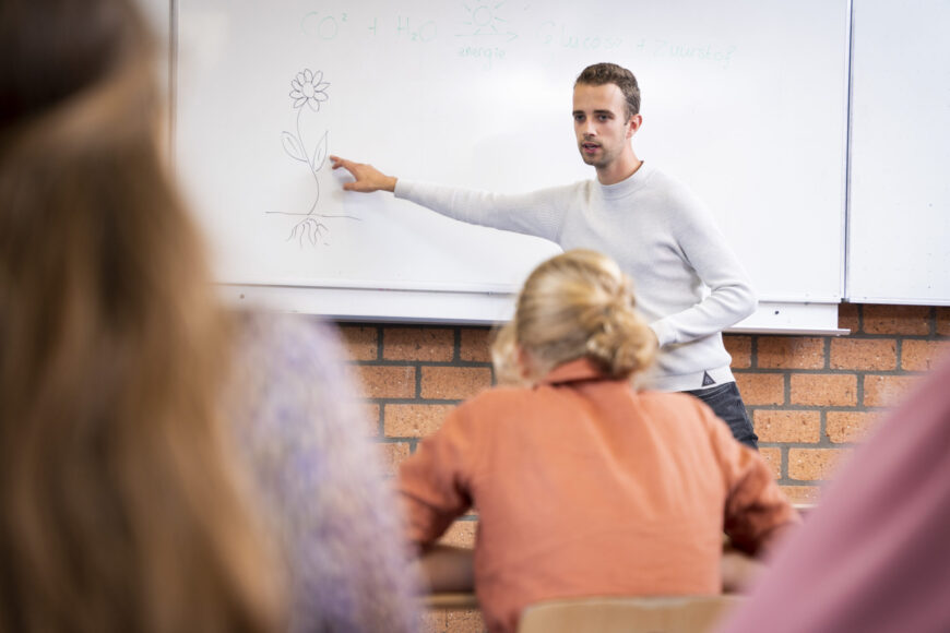 Docent geeft les biologie en wijst naar iets op het schoolbord