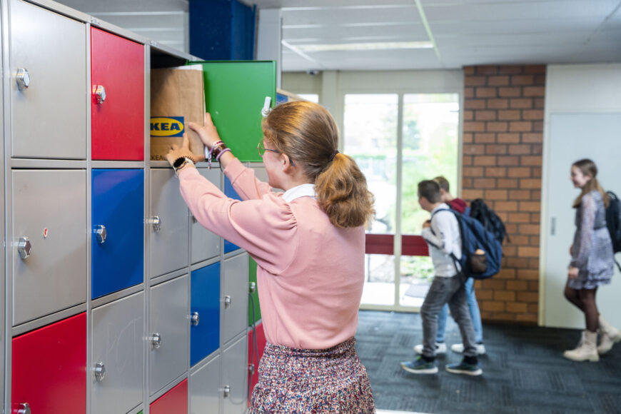 Meisje stopt boeken in kluisje.