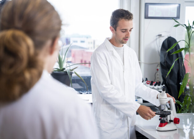 Docent demonstreert hoe een microscoop werkt in de biologieles.
