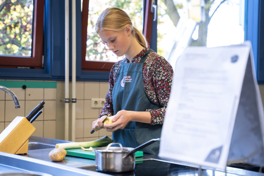 Leerling van de afdeling zorg en welzijn is aan het koken in het verzorgingslokaal op locatie Krabbendijke Kerkpolder