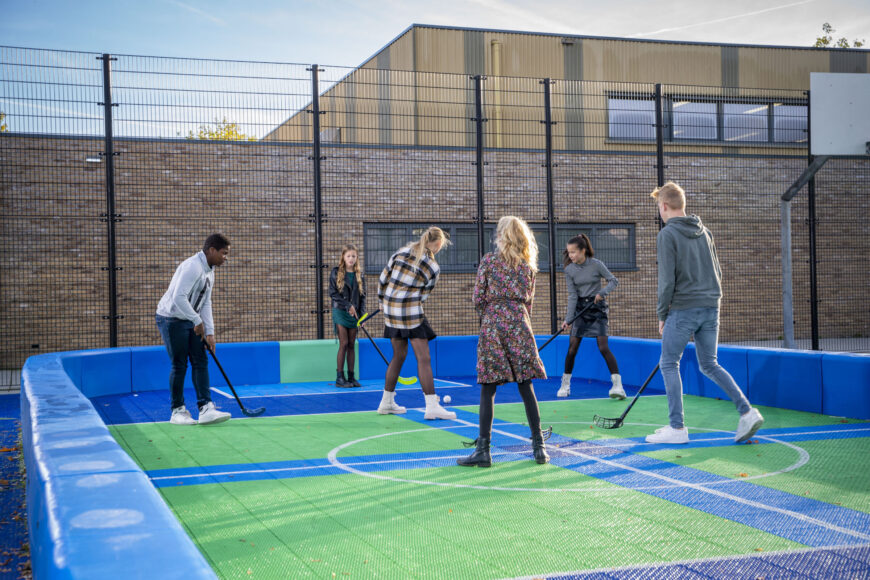 Leerlingen in hockeyveld spelen een spelletje hockey