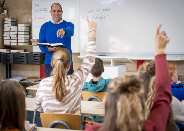 Docent geeft godsdienstles en wijst een leerling aan.