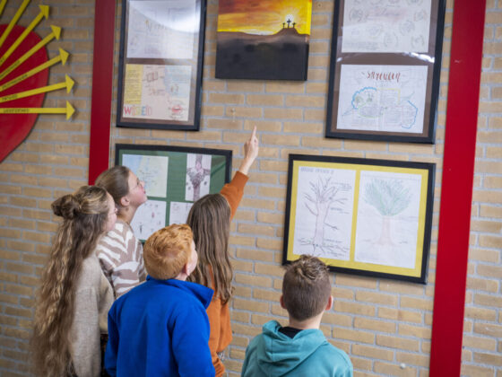 Leerlingen in een klaslokaal kijkend en wijzend naar een schilderij.