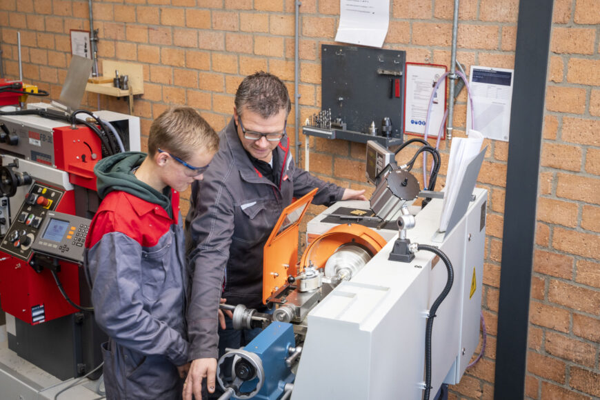 Docent geeft uitleg aan leerling over machine op de afdeling produceren, installeren en energie