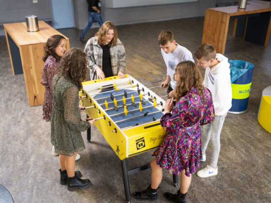 Leerlingen rond de voetbaltafel in de aula